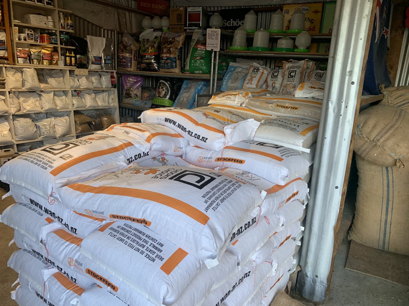 Chooks Choice, Chook Grow and rabbit pellet sacks, with poultry drinkers on the shelf above